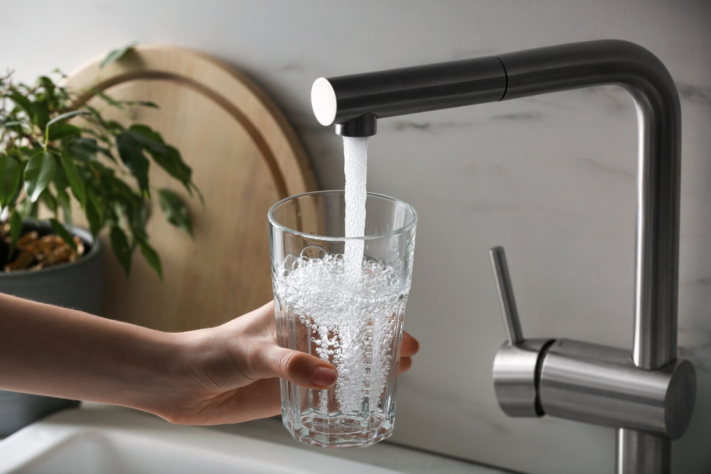 a person getting drinking water from the tap