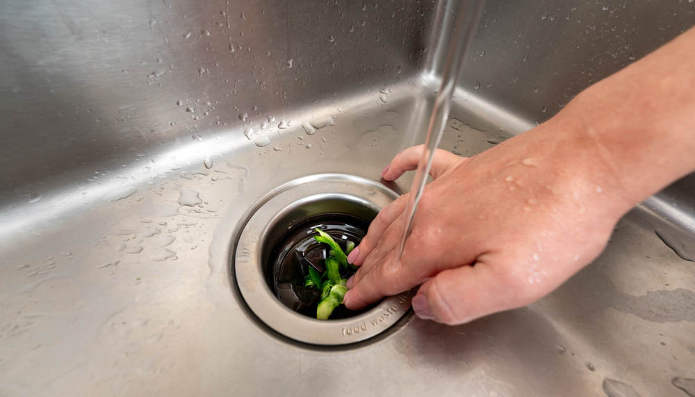 food scraps being thrown into a garbage disposal unit
